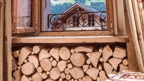 Una habitación con ventana que da a un paisaje montañoso, pared de troncos de madera y baranda de metal.