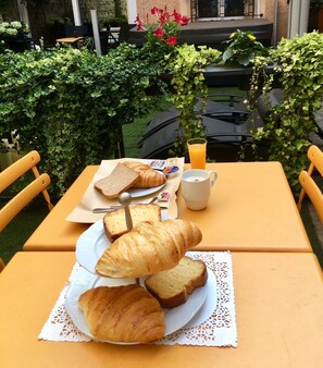 A table with croissants, bread, a jug of orange juice, and a small bowl of jam. - Les Suites de Vanves (Vanves)