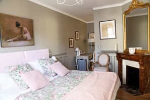 A bedroom with a bed, a desk, a chair, a fireplace, and a large mirror. - Les Suites de Vanves (Vanves)