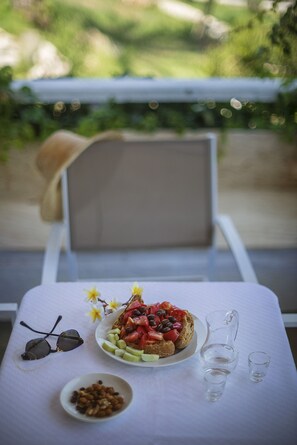 Una mesa con un plato de comida, una jarrón, un tazón pequeño de nueces y un par de gafas de sol.