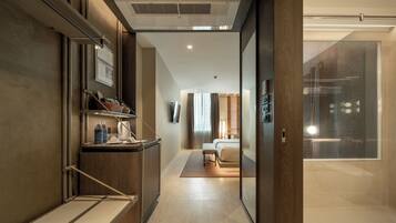A modern hotel room with a wooden desk, a bed, and a glass shower area.