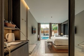A modern hotel room with a large bed, a desk with a kettle, a TV, and a view of a swimming pool. - Grand Vista Hotel Chiangrai (Chiang Rai)