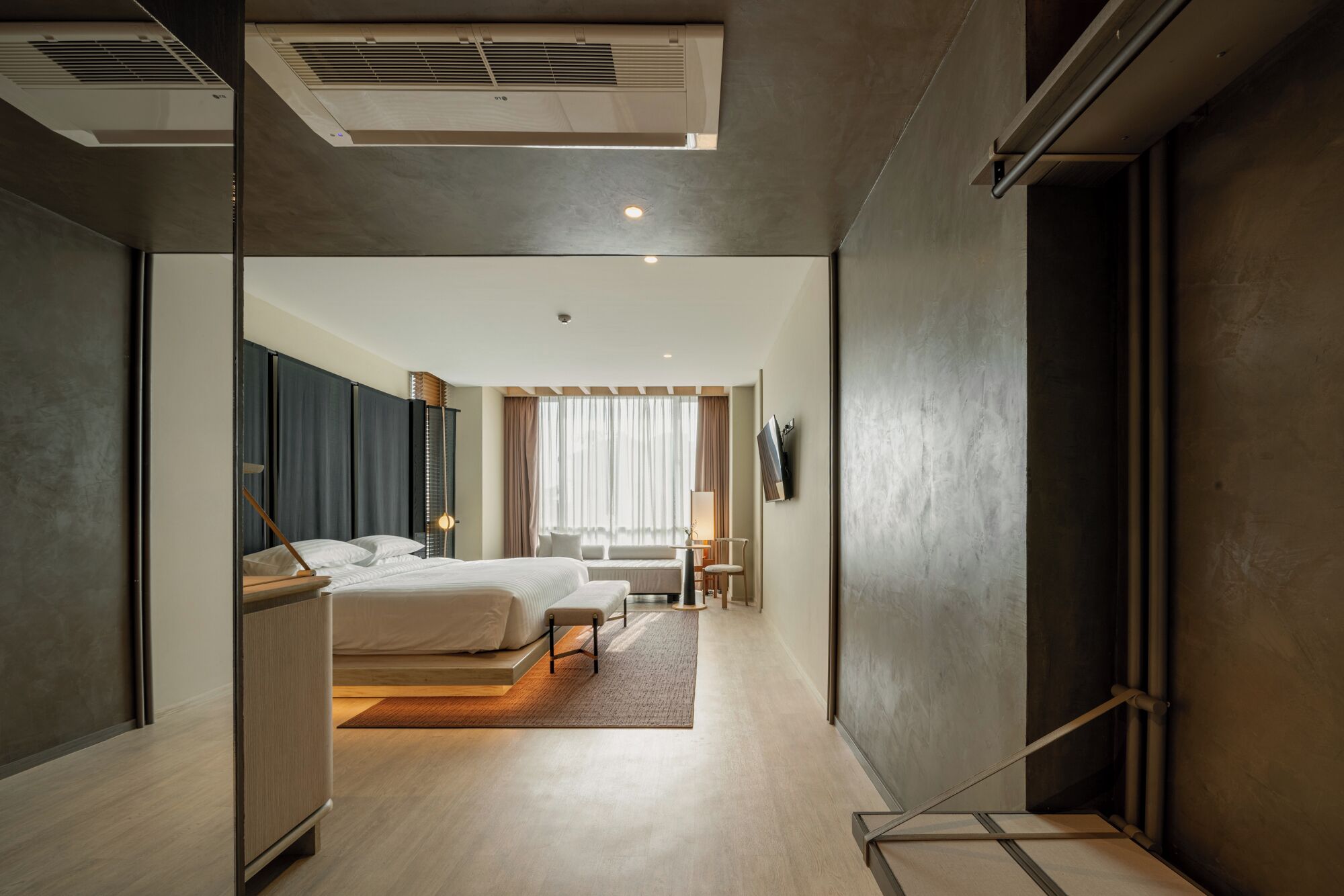 A modern hotel room with a large bed, a desk, and a view of the city.