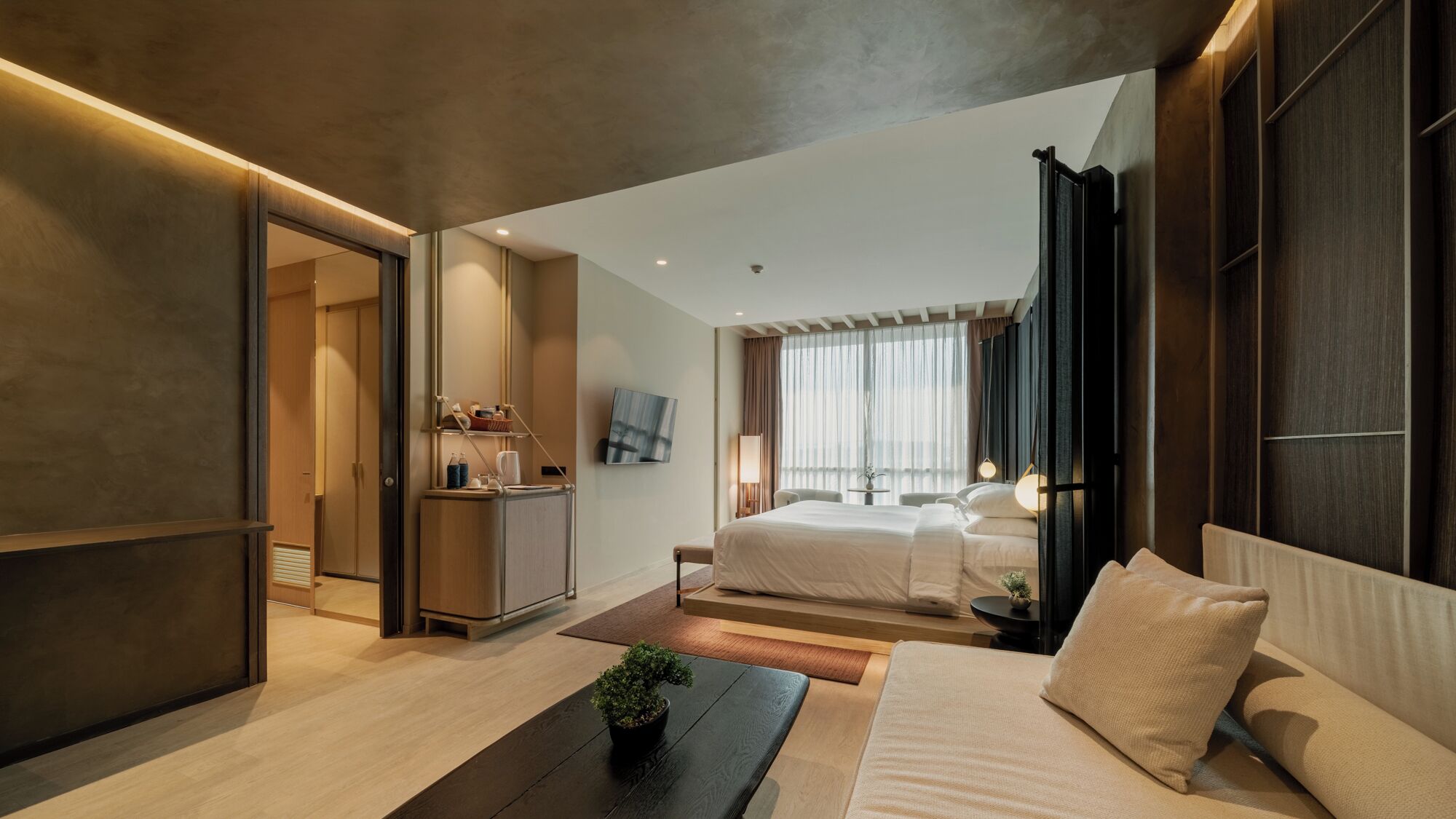 Una habitación de hotel moderna con una cama grande, un escritorio, un televisor y vistas a la ciudad.