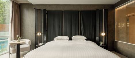 Un dormitorio moderno con una cama grande, una mesita redonda y vista a una piscina.
