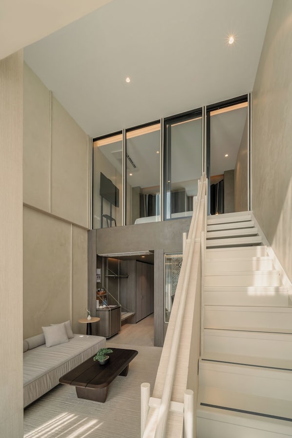 A modern interior with a staircase, a sofa, a coffee table, and a kitchen area.