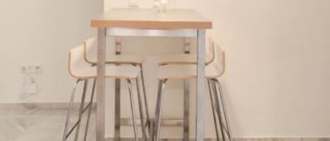 A minimalist dining area with a table and four bar stools.