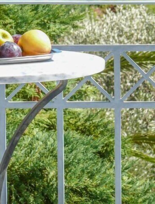 A round table with a white marble top, set outdoors with a metal railing.
