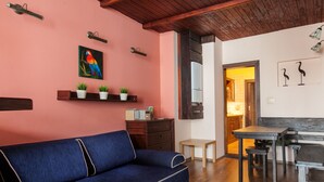 A cozy living area with a blue sofa, wooden coffee table, and a kitchen area with a wooden bench. - EchoDom 5 Apartments Florianska (Kraków)