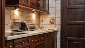 A kitchen with wooden cabinets, a built-in toaster, and a tiled backsplash. - EchoDom 5 Apartments Florianska (Kraków)