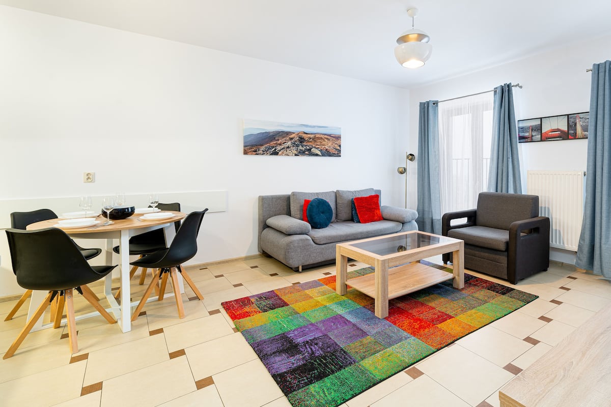 Ein modernes Wohnzimmer mit Essbereich, einer Couch, einem Couchtisch und einem Fernseher.
