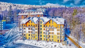 A multi-story hotel with a central courtyard, surrounded by snow-covered trees and a clear sky. - Sun & Snow Resort Sudety (Szklarska Poreba)