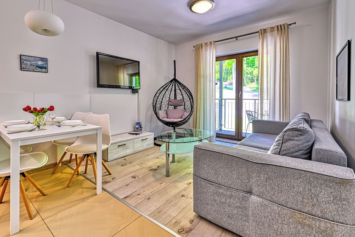 Ein modernes Wohnzimmer mit Essbereich, einem Hängekorbstuhl und einem Sofa.