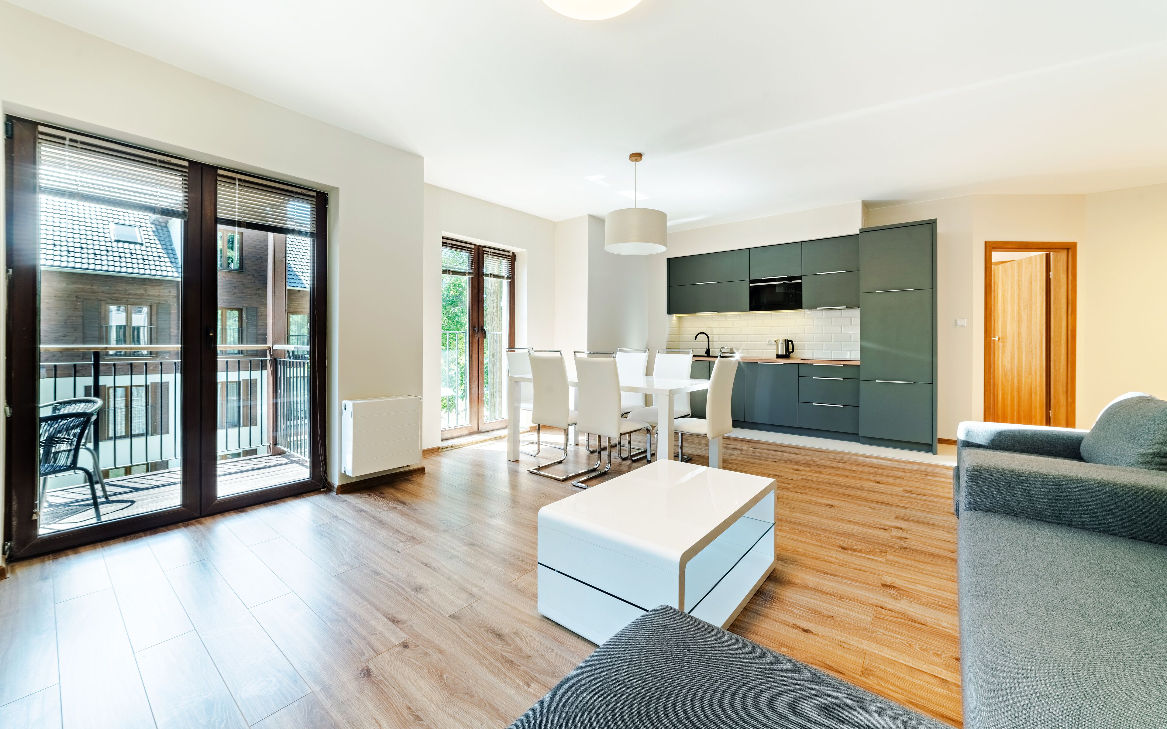 A modern apartment with a dining area, kitchen, and balcony.