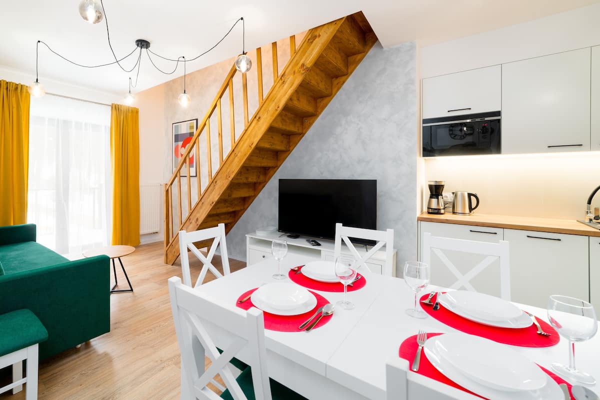Eine moderne Wohnung mit Essbereich, Wohnzimmer, Küche und einer Holztreppe.