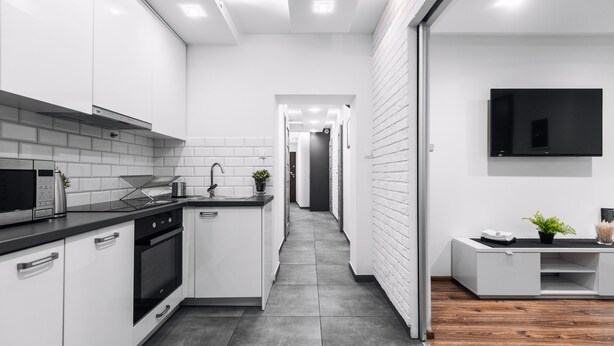 A modern kitchen with white cabinets, a black countertop, and a built-in oven.
