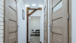 A hallway with wooden doors, a tiled floor, and a framed picture on the wall.