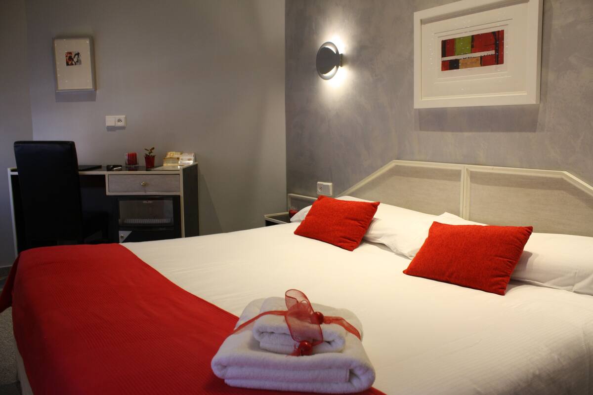 A hotel room with a neatly made bed, a desk, and a chair.