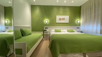 Habitación de hotel con dos camas, ropa de cama verde, una mesita de noche con teléfono, un cuadro en la pared y una ventana con cortinas.