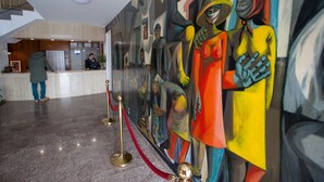 A lobby with a reception desk, a staircase, and a colorful abstract mural. - Hotel Ínsula Barataria (Alcazar de San Juan)