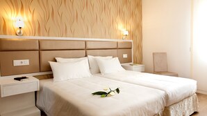 A double bed with a beige headboard, two bedside tables, and a nightstand with a lamp. - Hotel Ínsula Barataria (Alcazar de San Juan)