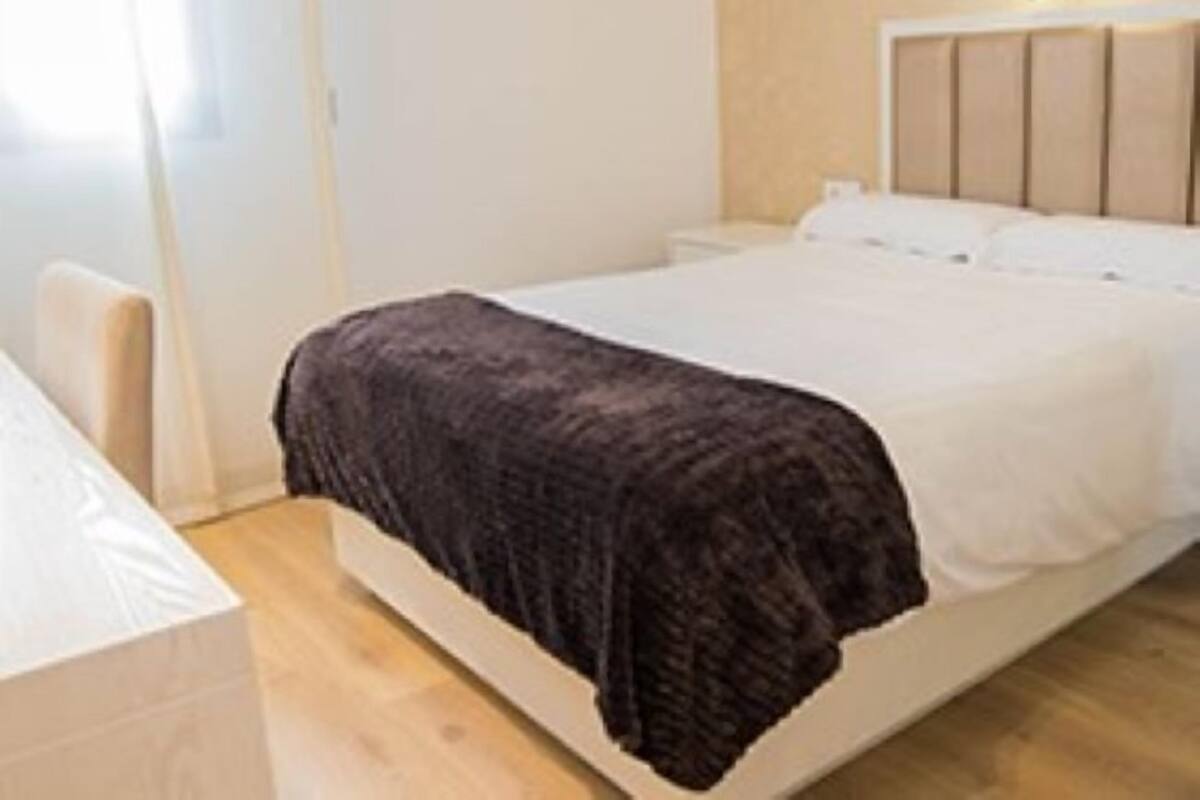 A modern bedroom with a bed, bedside table, and a headboard with a light fixture.