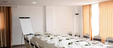 A conference room with a long table set for a meeting, equipped with a projector and a whiteboard.