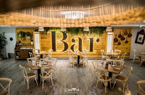 A restaurant interior with a large 'Bar' sign, wooden tables, wicker chairs, and a wooden ceiling. - Hotel Ínsula Barataria (Alcazar de San Juan)