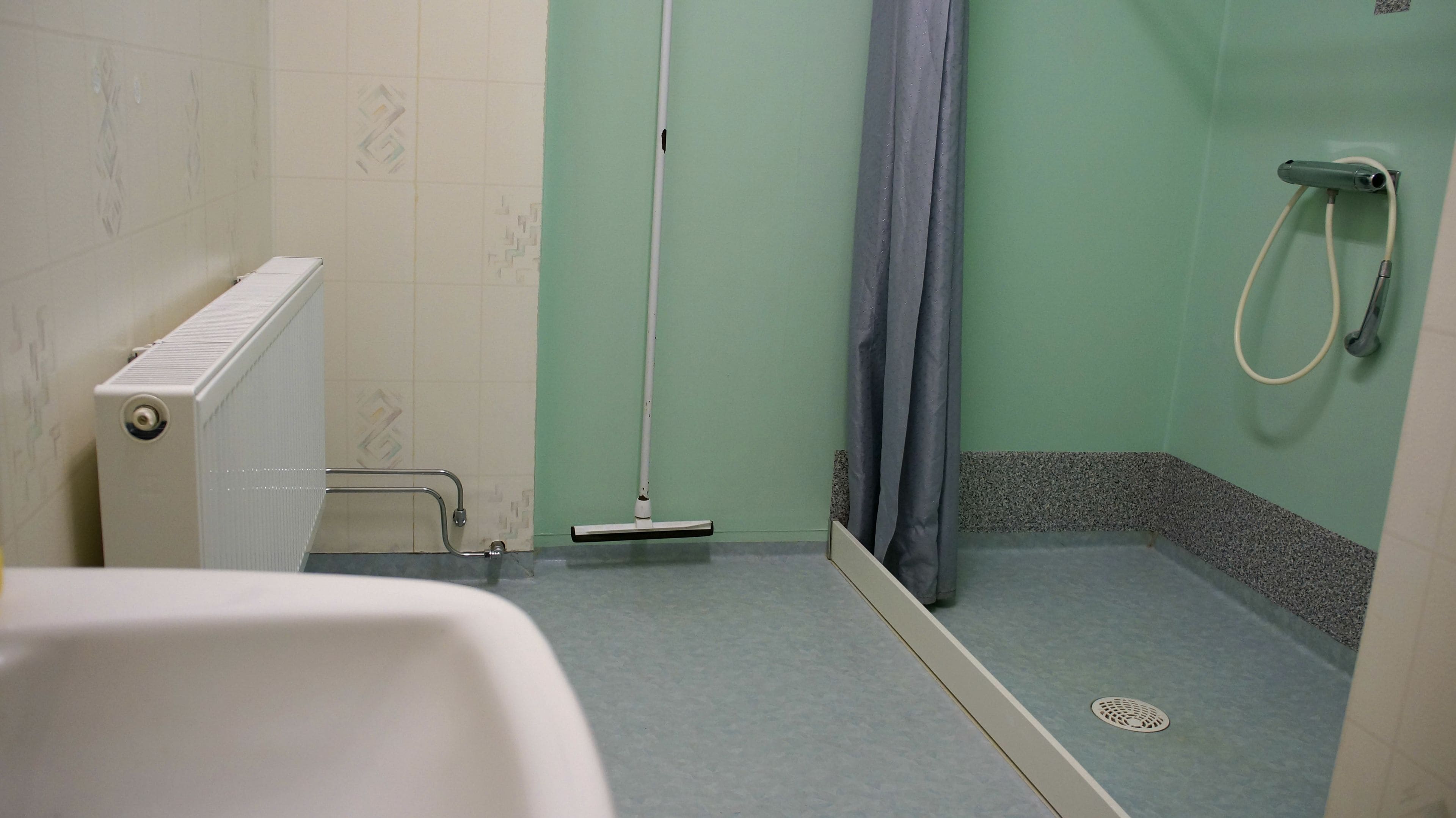 Un baño con ducha, inodoro y radiador.