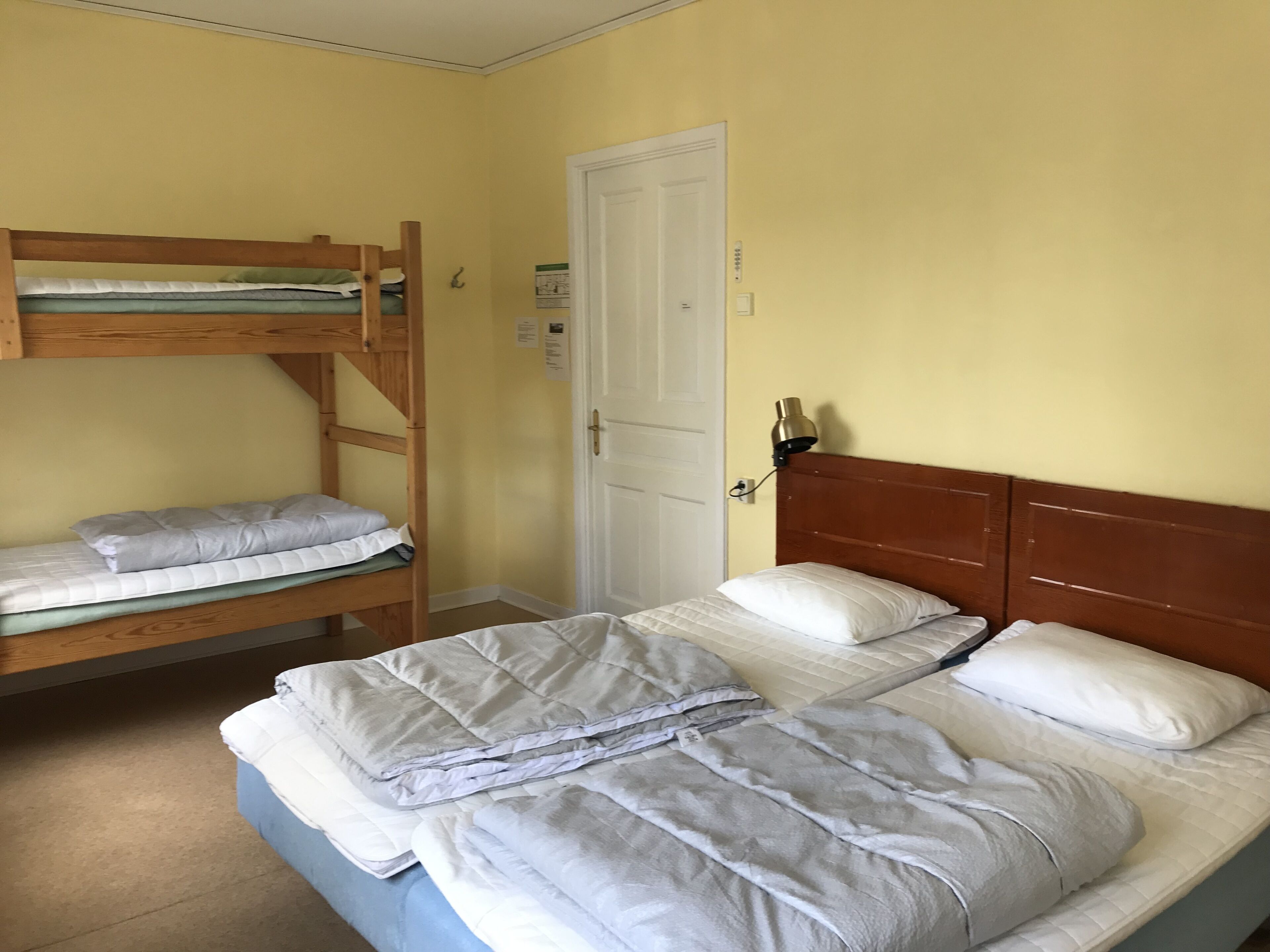 Une pièce avec un lit superposé, un lit simple et une porte.
