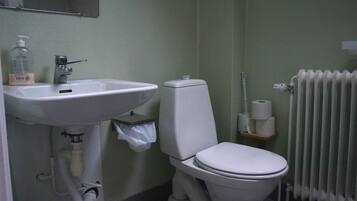 Un baño con lavamanos, inodoro y radiador blancos.