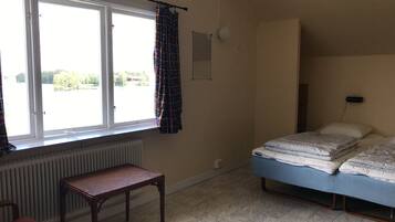 A room with a bed, a chair, a radiator, and a window with curtains.