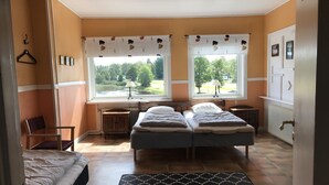 Een kamer met twee bedden, een stoel, een bureau en uitzicht op een meer door grote ramen.