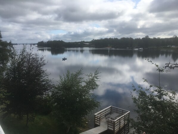 A calm lake with a wooden dock and a small boat.