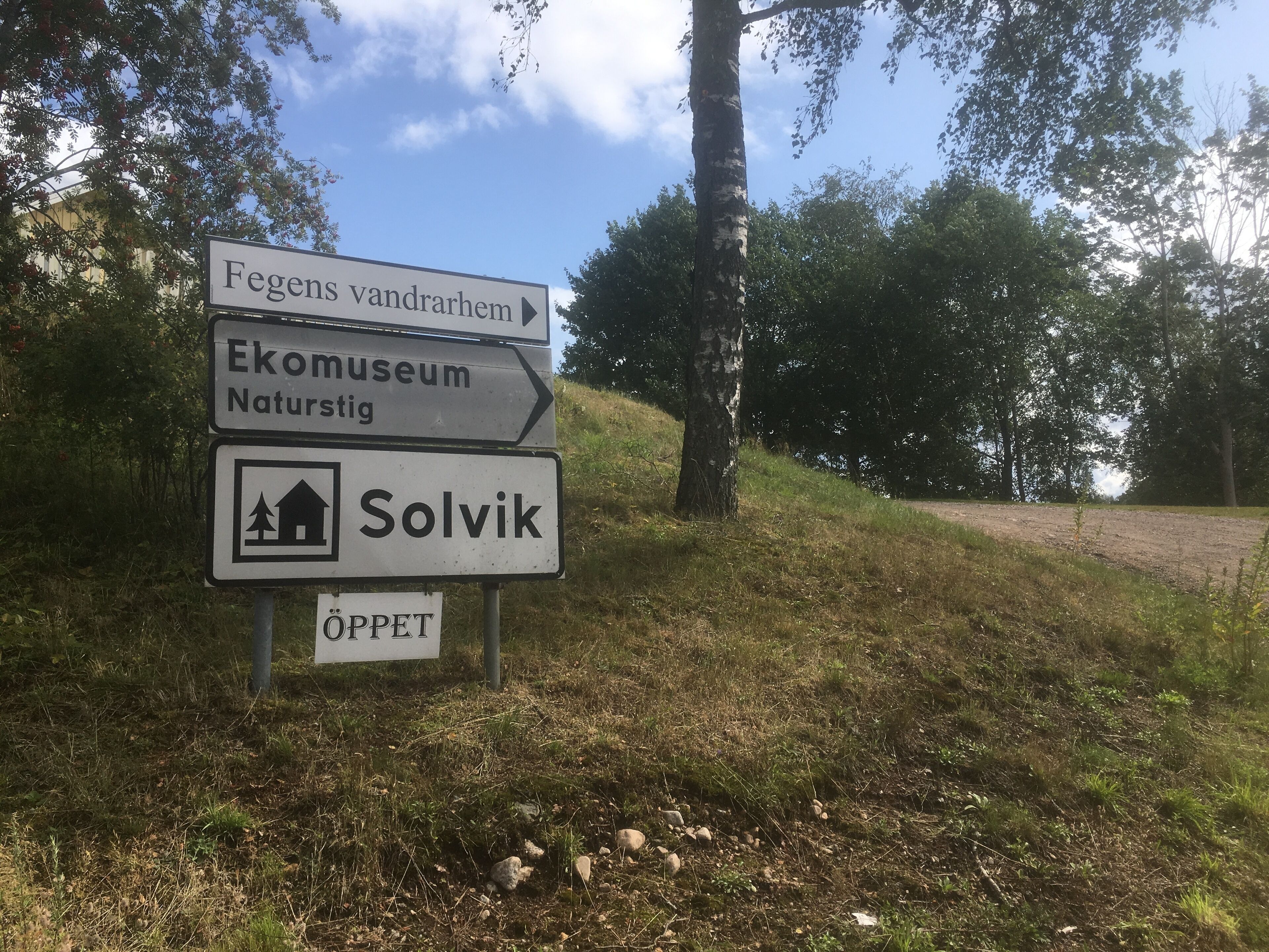 Señal direccional con flechas indicando 'Fegens vandrarhem', 'Ekomuseum Naturstig' y 'Solvik'.