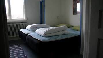 Quarto com duas camas, um radiador e uma janela.