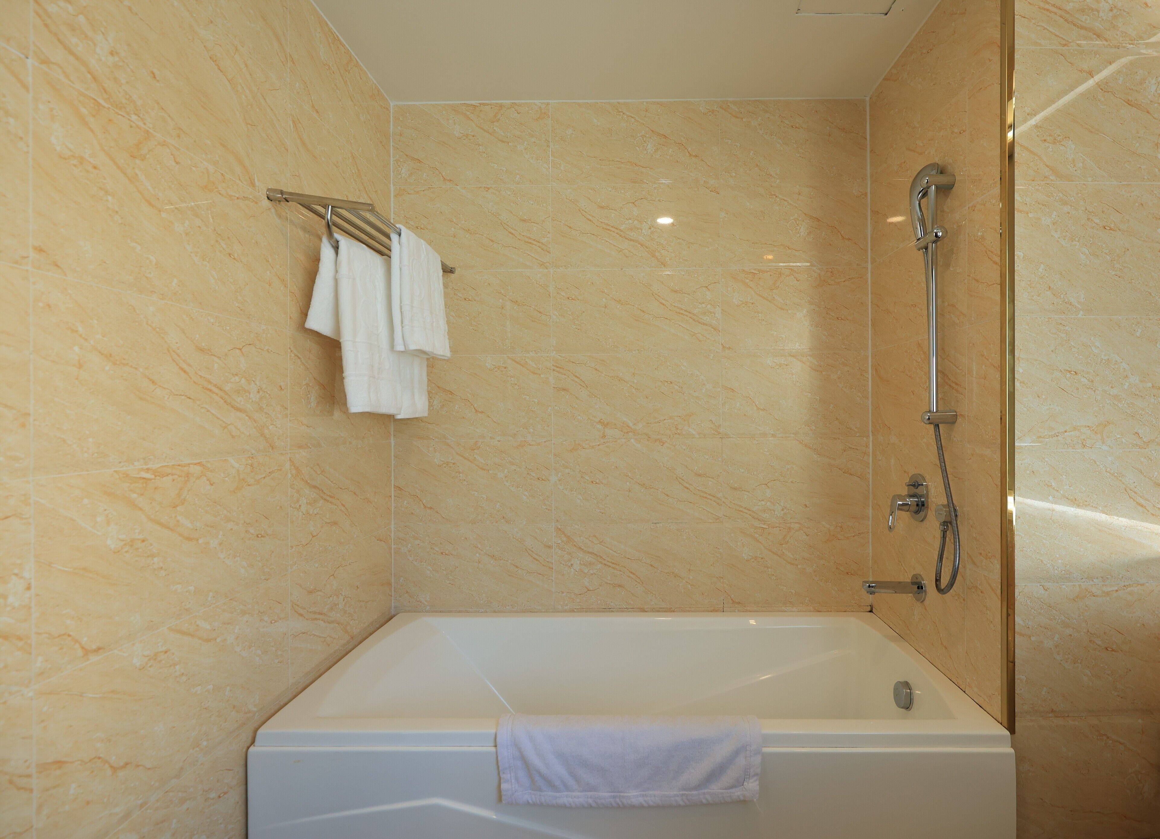 Een moderne badkamer met een marmeren wand, een badkuip en een douche.
