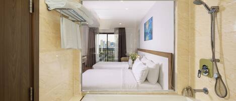 A hotel bathroom with a large bathtub, a shower, and a view of a cityscape through the window.