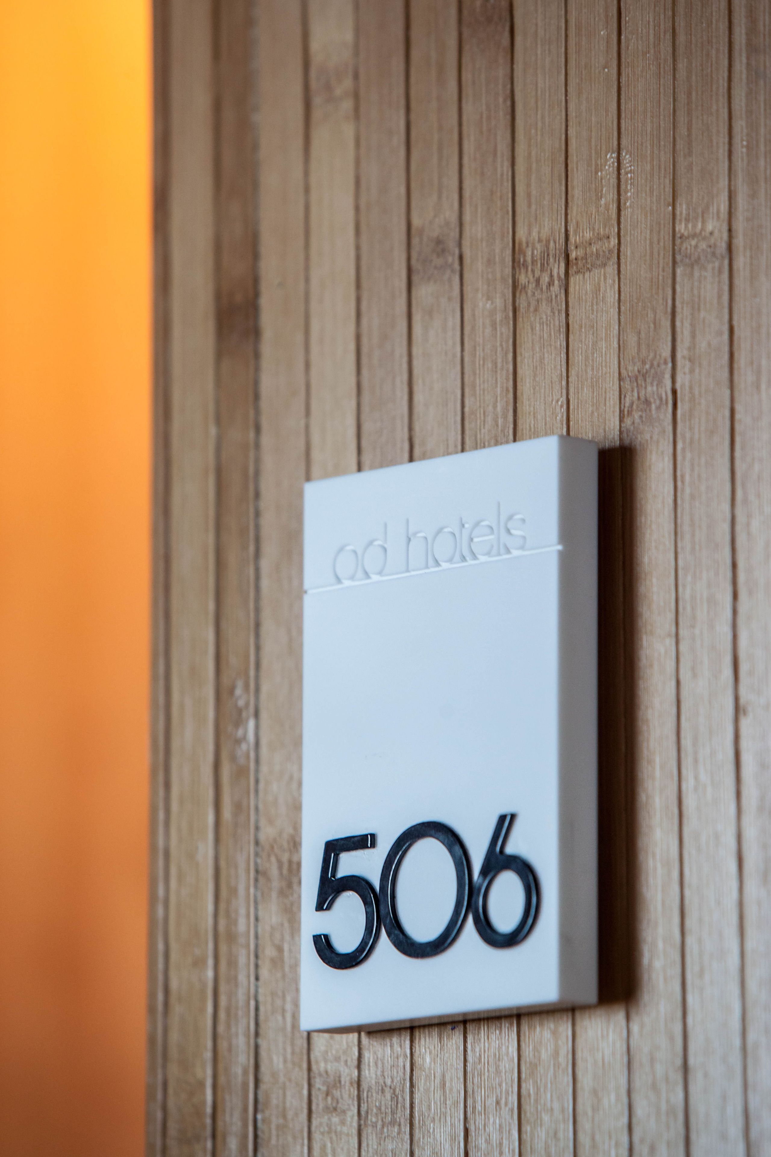 Un letrero blanco de hotel con el número 506 y el texto 'od hotels' en una pared de madera.