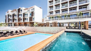 Relax by the pool surrounded by comfortable lounge chairs and umbrellas.
