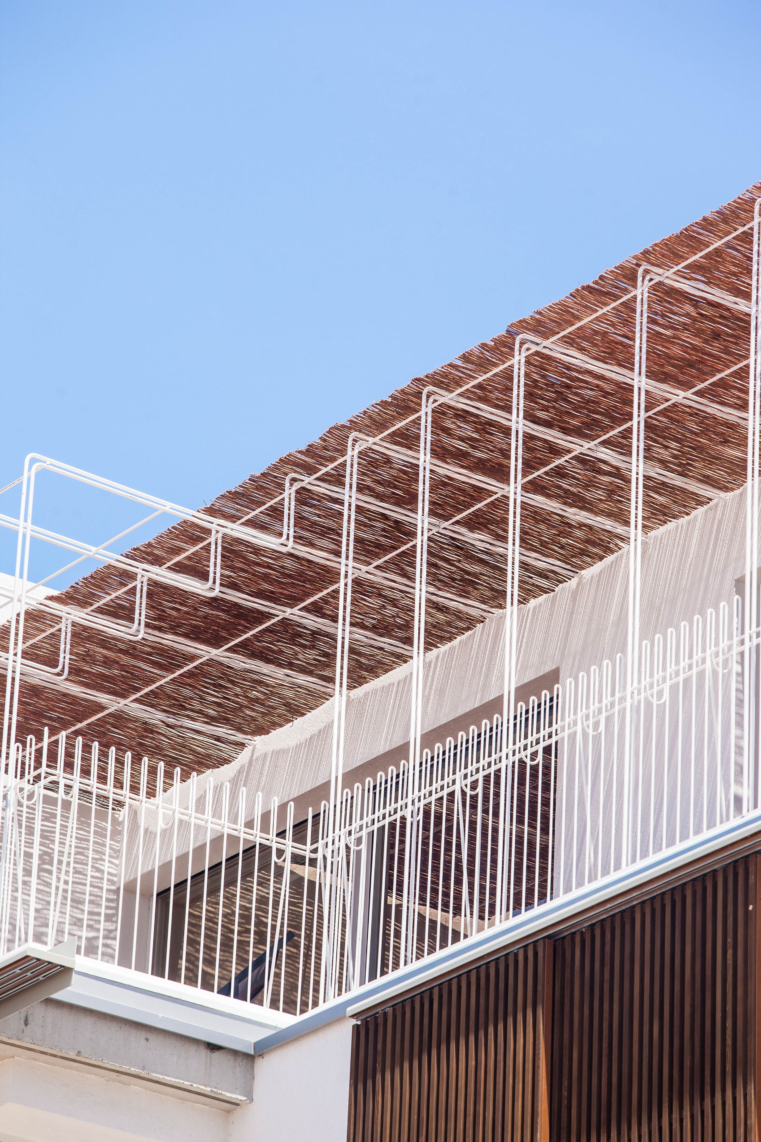 Un edificio con techo inclinado y barandilla de metal blanco.