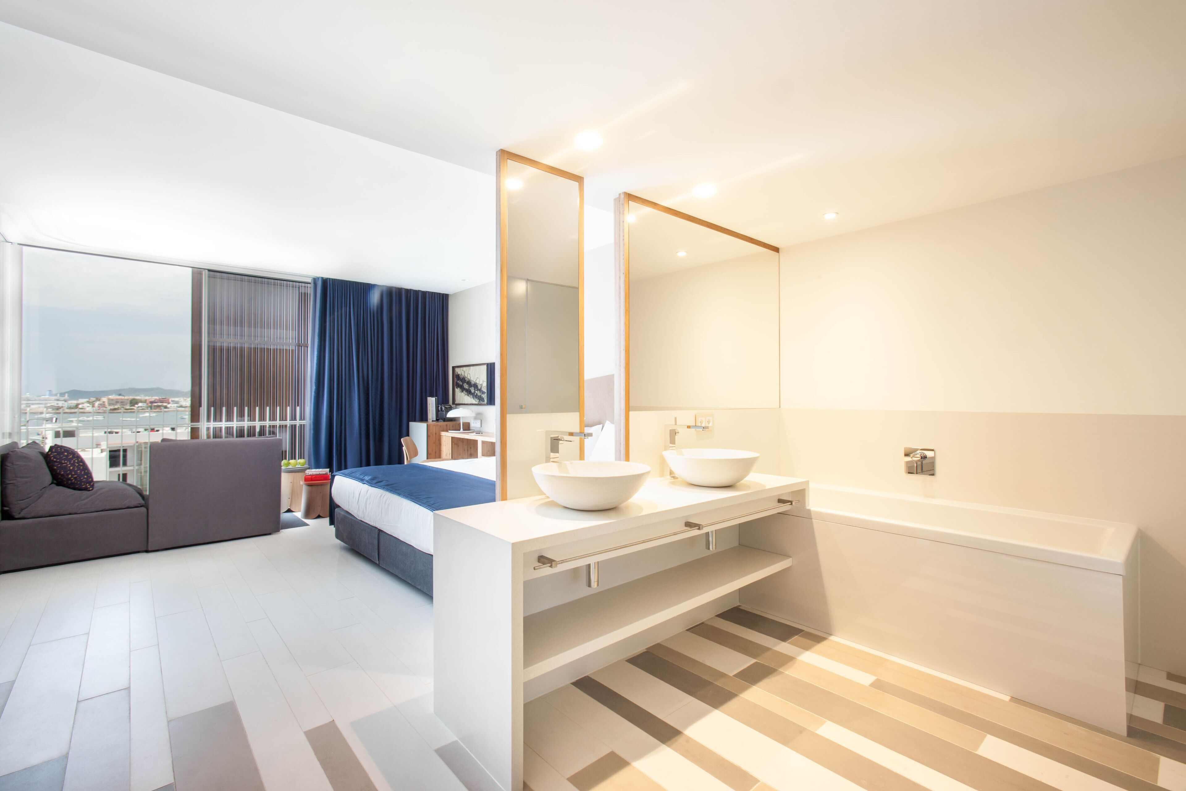 Une salle de bain moderne avec un grand miroir, deux lavabos et une baignoire.