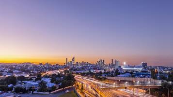 A cityscape at dusk with a prominent skyline, a highway with light trails, and residential areas.