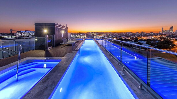 Une piscine sur le toit offrant une vue sur la ville au crépuscule.
