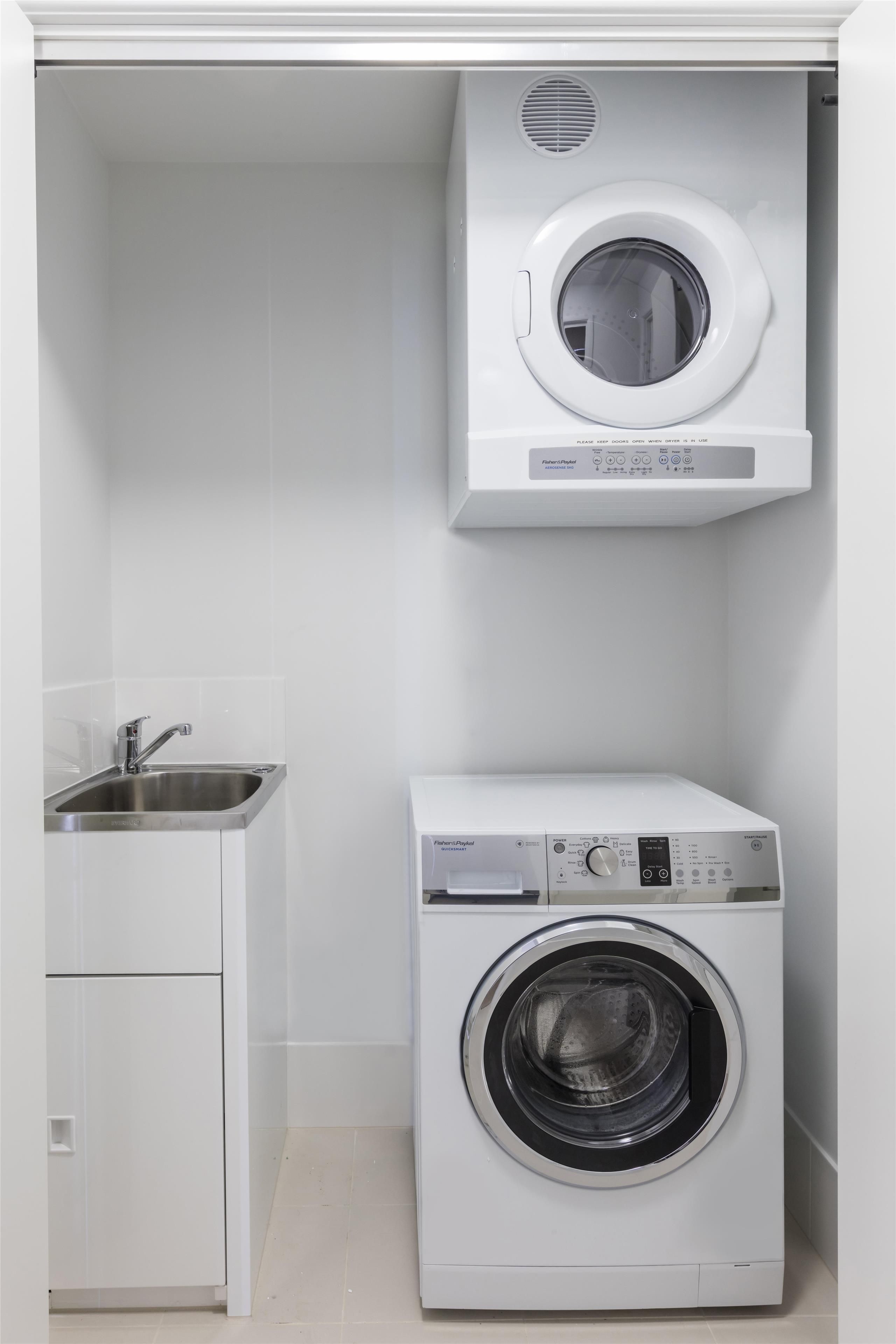 Une petite buanderie équipée d’un lave-linge à chargement frontal et d’un sèche-linge à chargement par le haut.