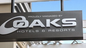 Segnaletica per OAKS Hotels & Resorts, design moderno e cielo sereno sullo sfondo.