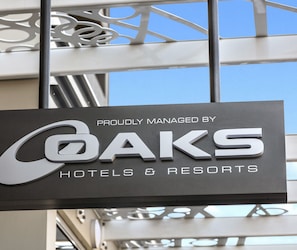 Segnaletica per OAKS Hotels & Resorts, design moderno e cielo sereno sullo sfondo.