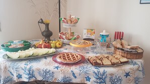 Et bord med forskellige spiser, herunder frugt, kager og brød.