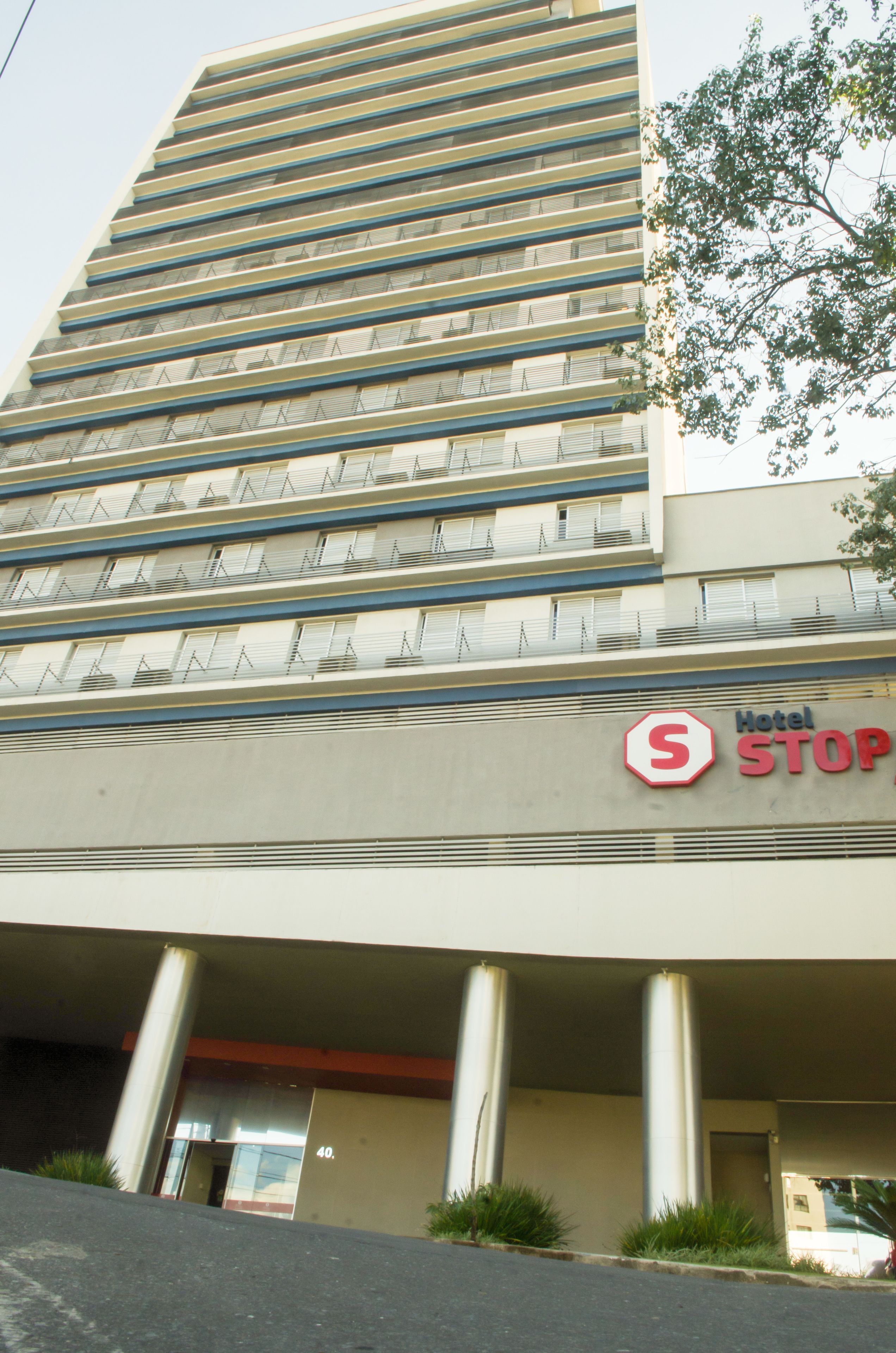A hotel with a modern design, featuring a prominent 'Hotel STOP' sign. The building has multiple floors with balconies and a flat facade.