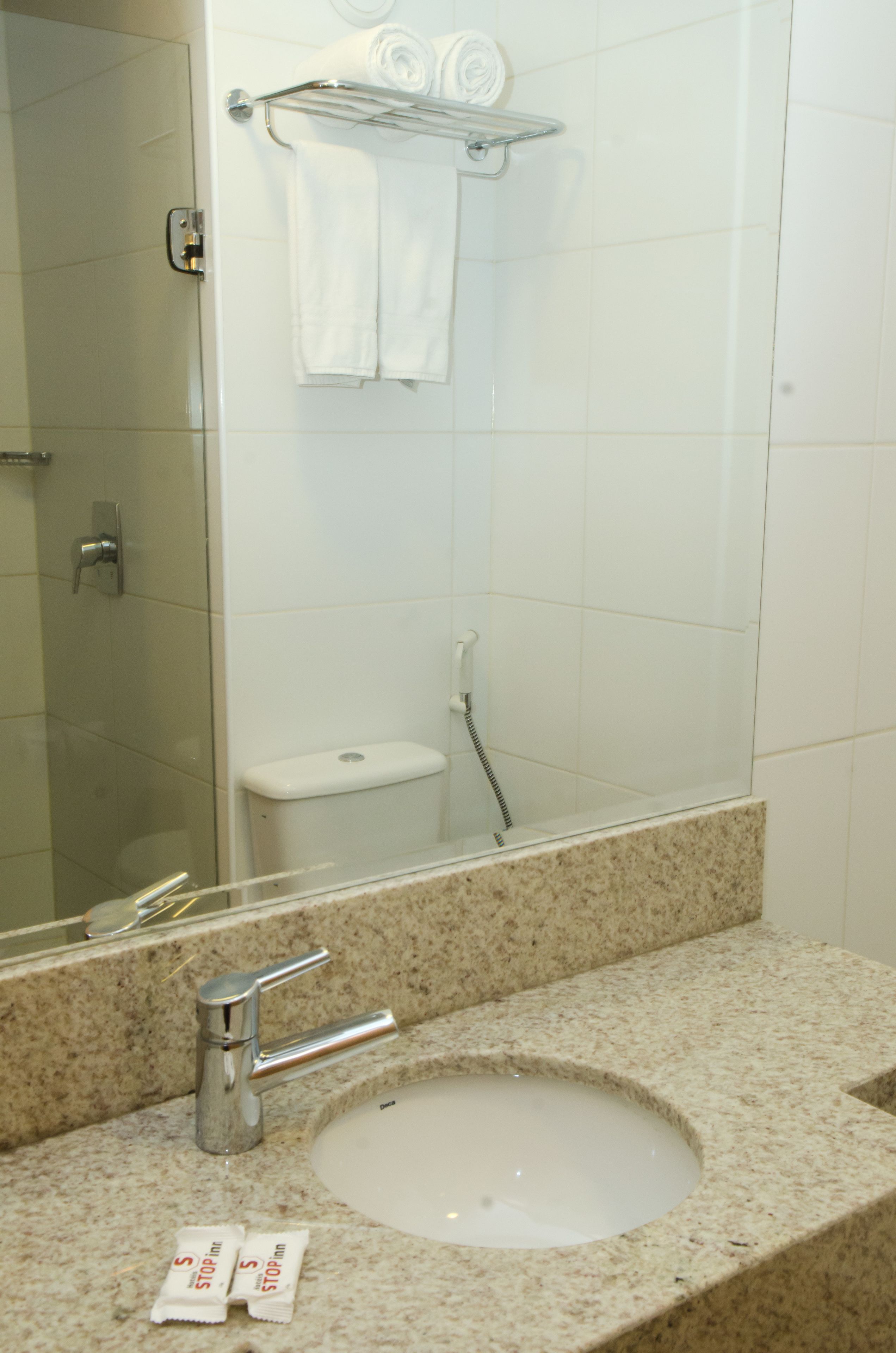 Een badkamer met een wastafel, spiegel en handdoekhouder.